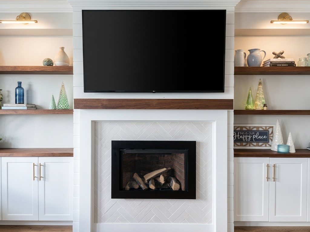 Custom living room built-in with a black-framed gas fireplace in a white herringbone tile surround, a black walnut mantel, and white shaker cabinets with black walnut shelves and countertops on each side